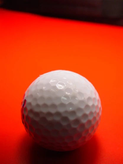 close up view of a white golf ball on a red background