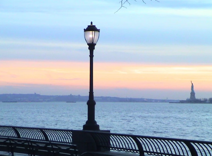 a street lamp next to a fence by water