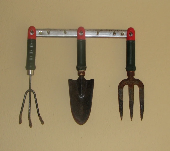 a hanging tool rack with three pairs of scissors on it