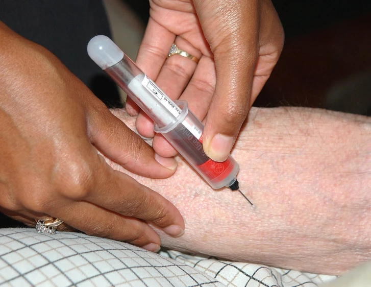 a person getting vaccinigraph on the leg of another persons leg