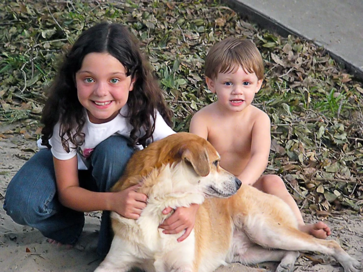 a young child sitting on the ground with a dog