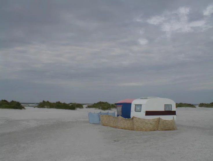 a white building with hay covering it in the sand