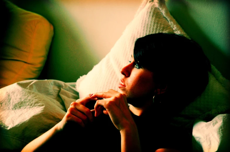 a woman laying in bed with pillows, a blanket and green walls