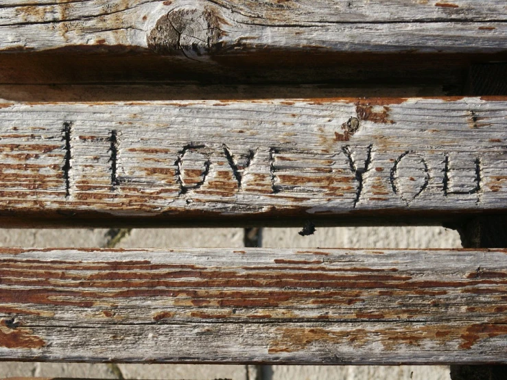 an old wooden bench with handwritten love you written on it