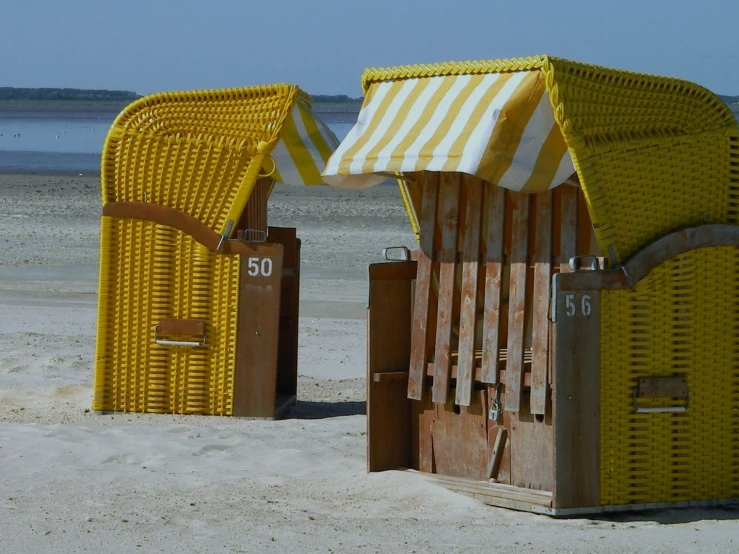 a couple of yellow and brown beach chairs in the sand