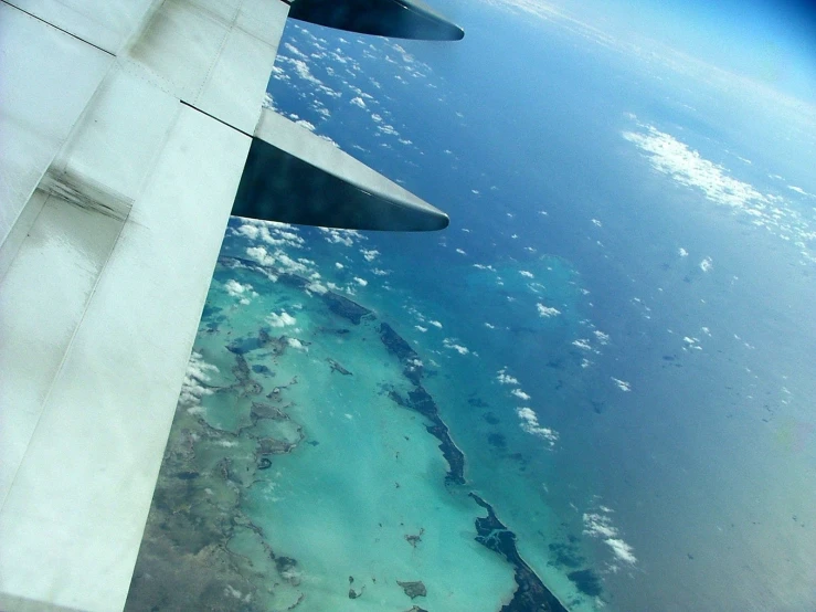 an airplane flying above some very blue water