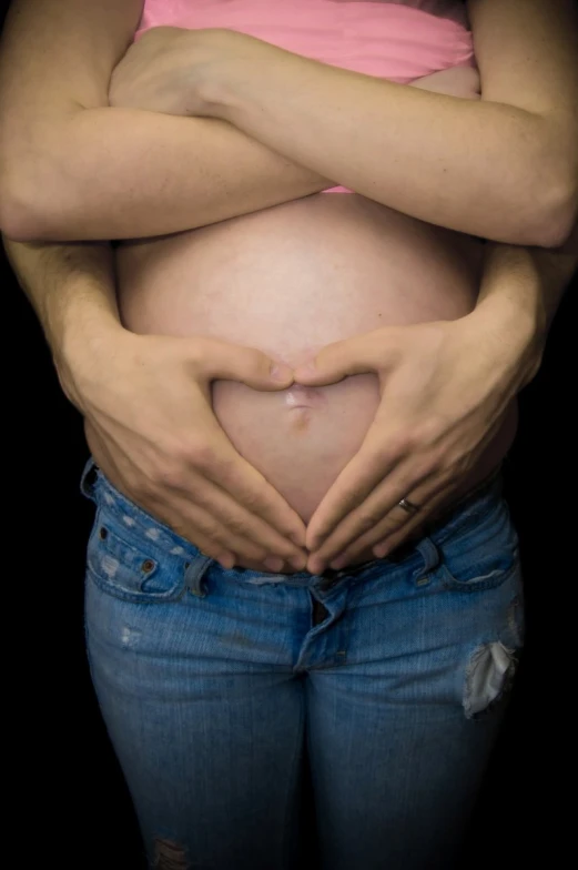 pregnant woman holding her belly to show the heart shape