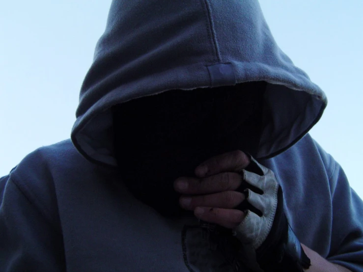 person in dark hoodie putting his hand under their nose