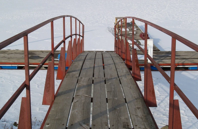 a long wooden footbridge next to snow covered ground