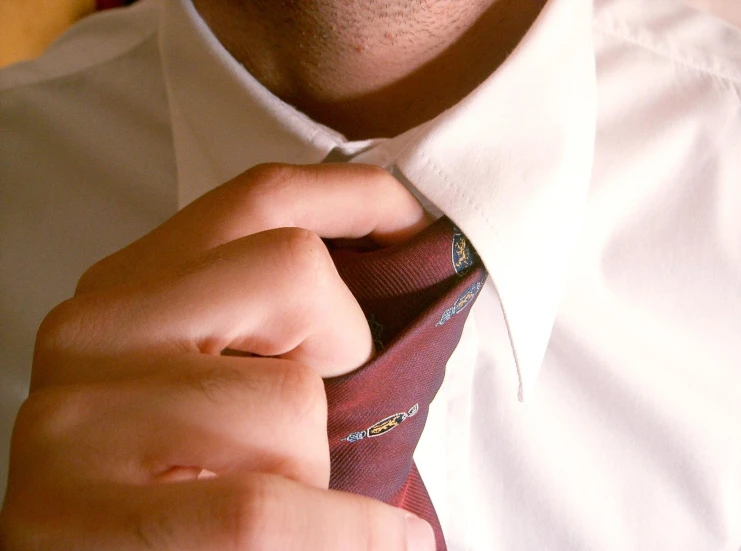 a man adjusting his tie while wearing a shirt