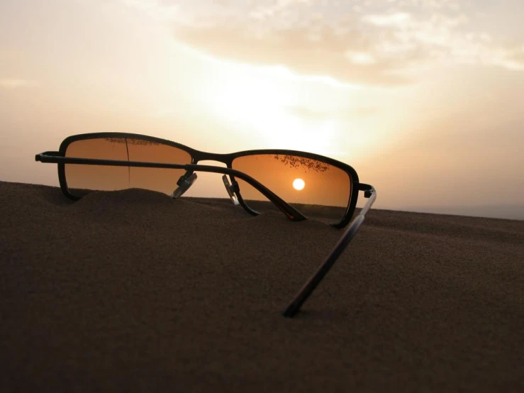 a pair of sunglasses sitting on top of a sand dune