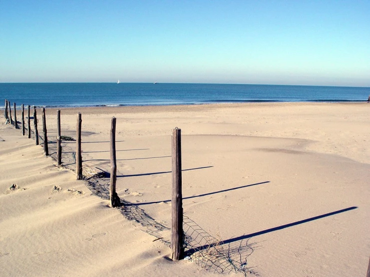 a line of beach fences stretching out into the ocean