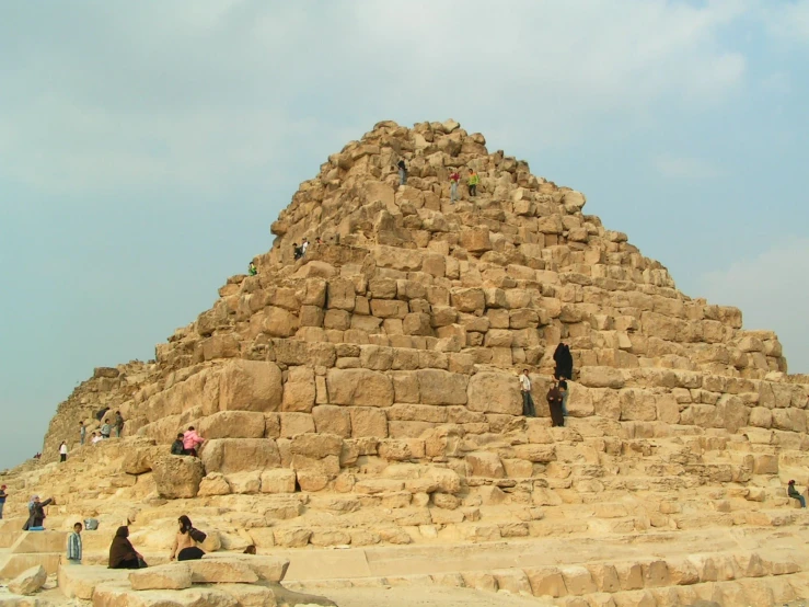 people walking on a large structure that has some sand stacked on top of it