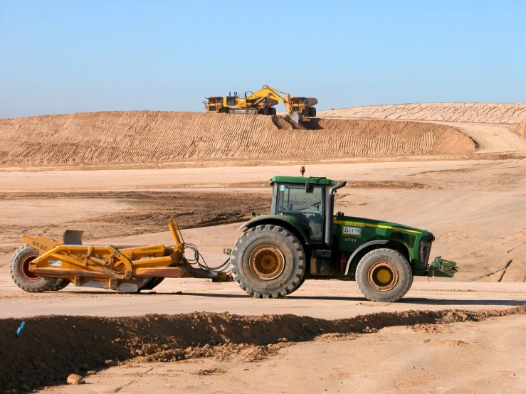 a tractor pulling a plow in a sandy field