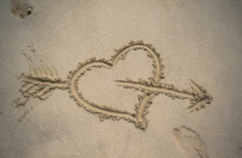 a heart and arrow drawn on the sand