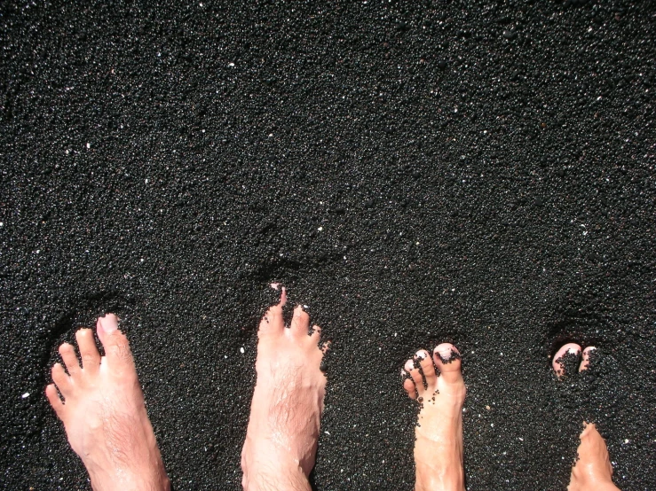 four pairs of feet with pinknails on the sand