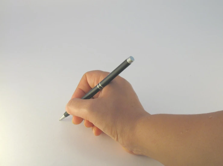 a person holding a pen over a white table