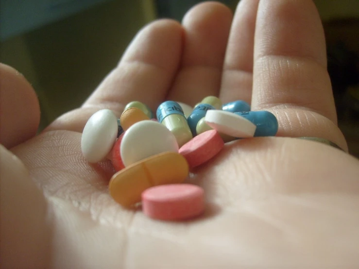 a person holding some colorful pills in their palm