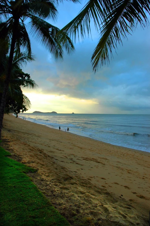 a beach with people out in the water and a cloudy sky