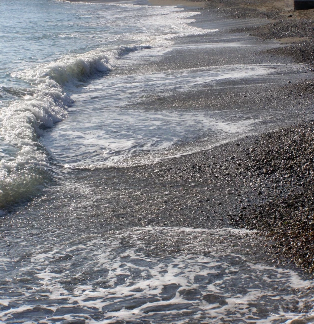 a large wave coming into the shore with people on it