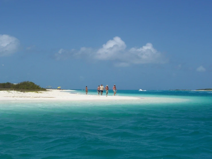 three people walking along an island in the middle of ocean