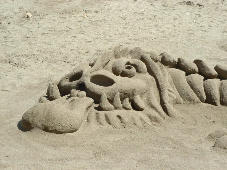 sand sculpture depicting a lion head and a crocodile mouth