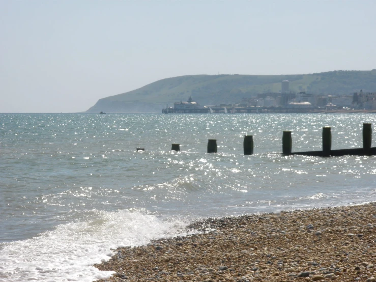 several pieces of wood sticking out of the ocean next to a pier