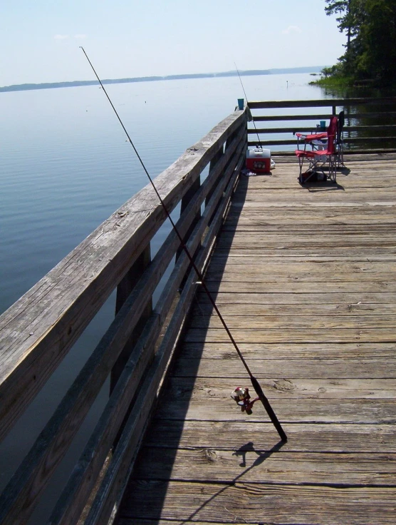 two chairs and two fishing rods on a pier