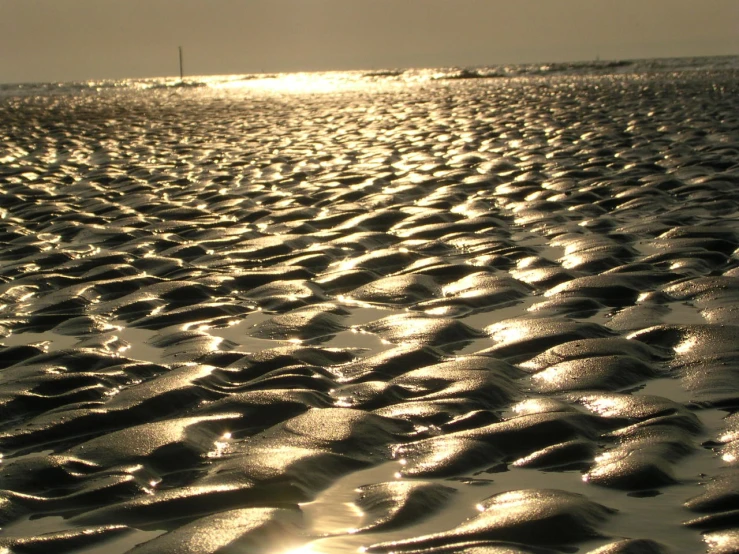 the ocean and the sky reflect on the beach sand