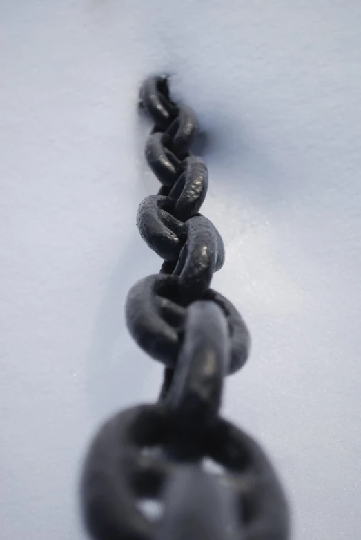 a black chain hangs from the surface on a white table