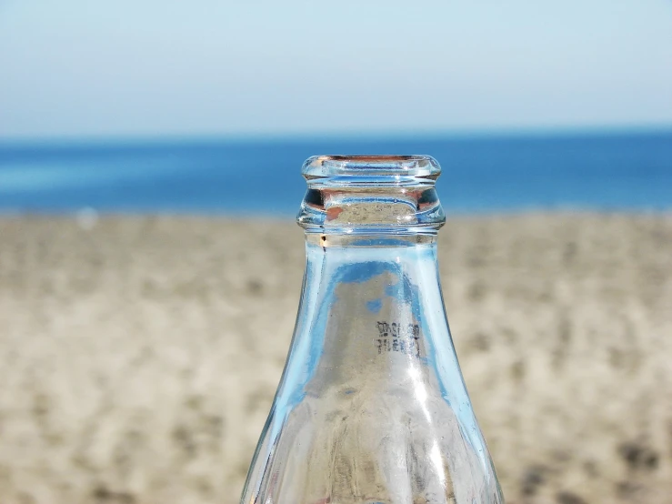 an empty bottle of water on top of the beach