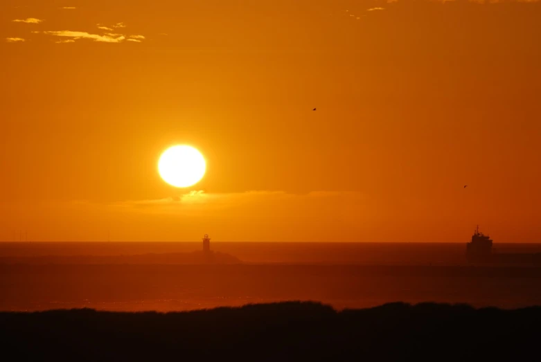 a large orange sun is set over some water