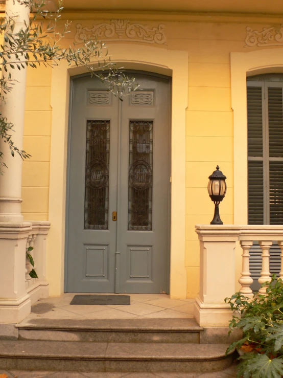 the front door to a home with columns, a light fixture, and blue doors