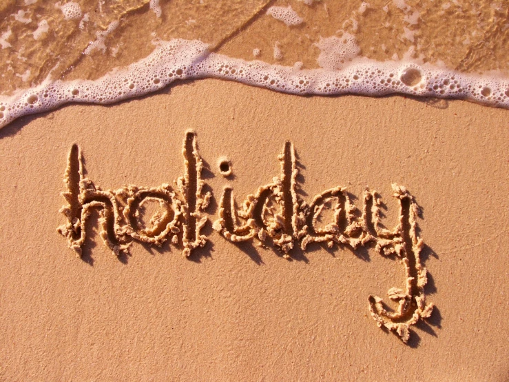 the word holiday written in sand on the beach