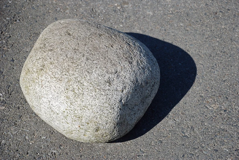 a rock on asphalt with sun shining through