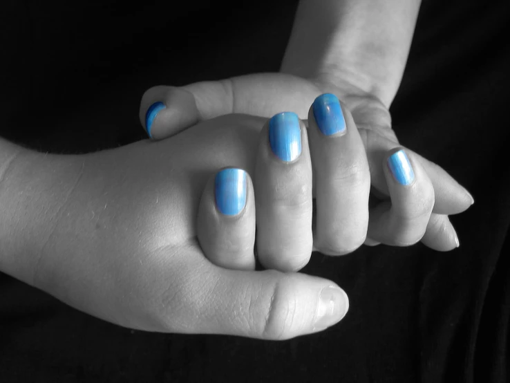 two hands with blue nail polish holding each other