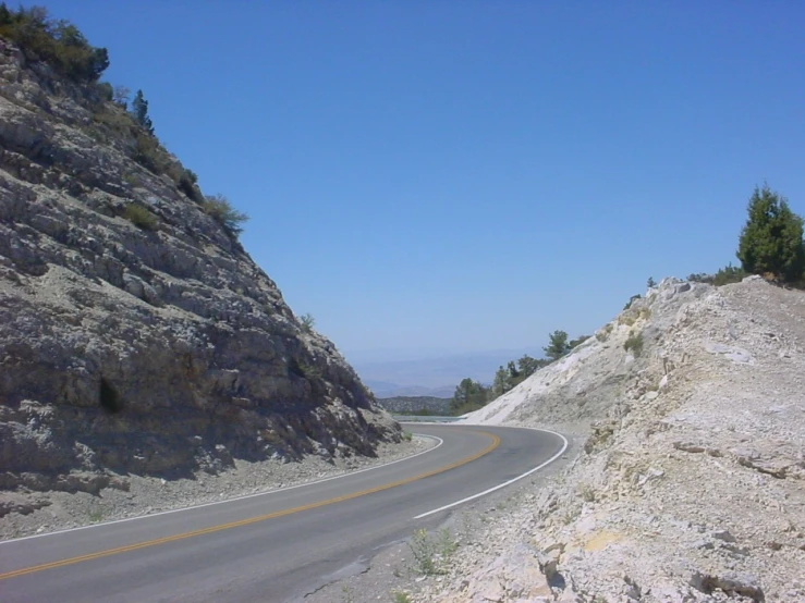 a curved road curves into the distance on the mountains