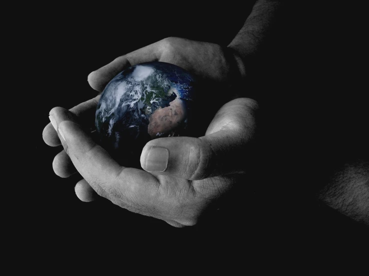 a hand holding the earth and two hands holding it