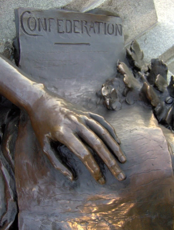 a statue of hands resting on a plaque