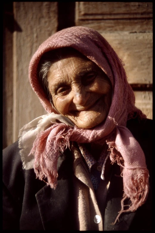 an elderly woman with a pink scarf around her neck