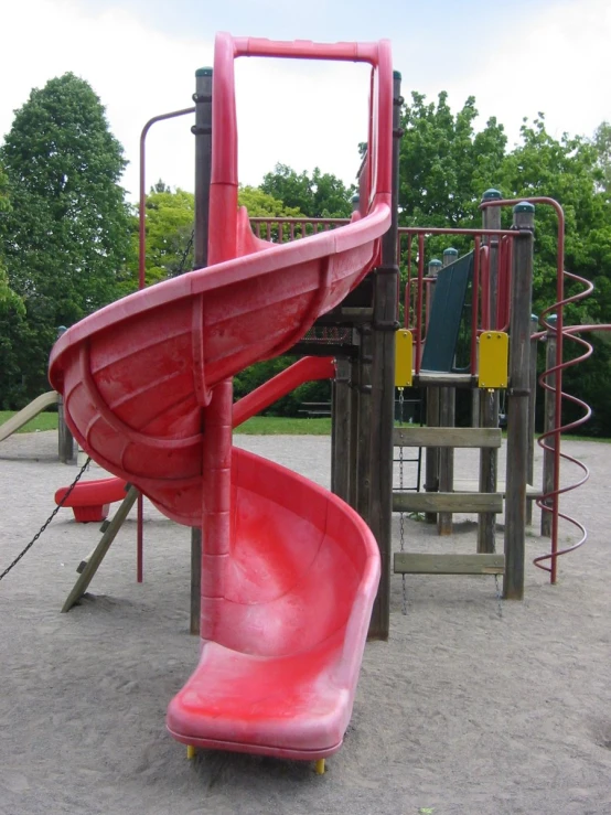 an empty playground has a pink slide next to a yellow object