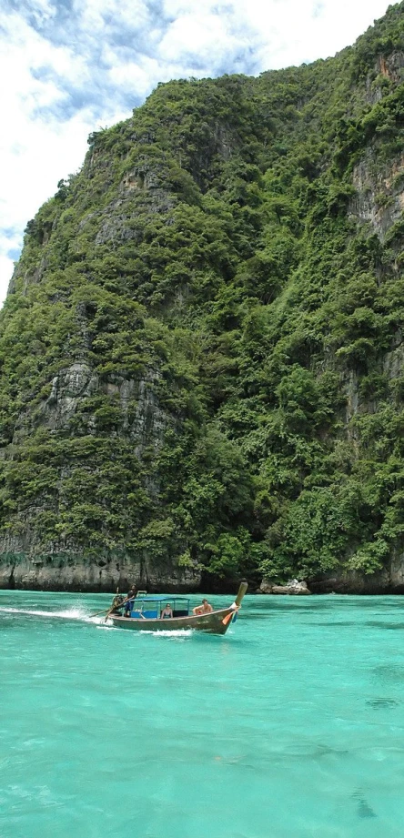 people are on boats sailing near a mountain