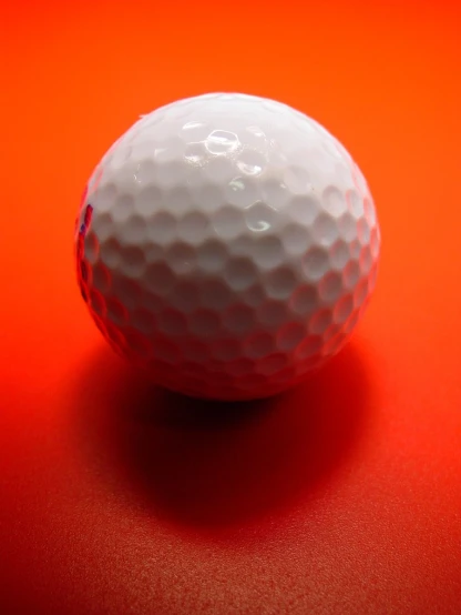 a golf ball sits on an orange surface