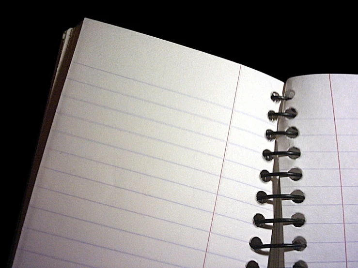 an open spiral notebook on a dark surface