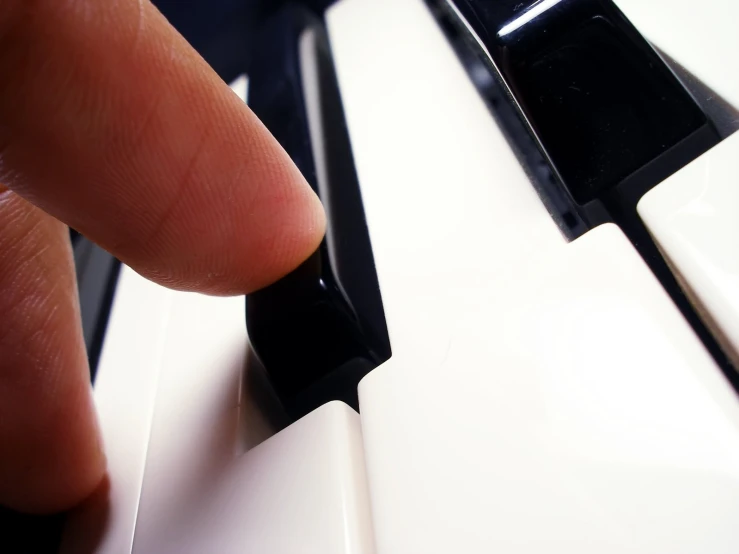 a finger touching a keyboard that is painted black