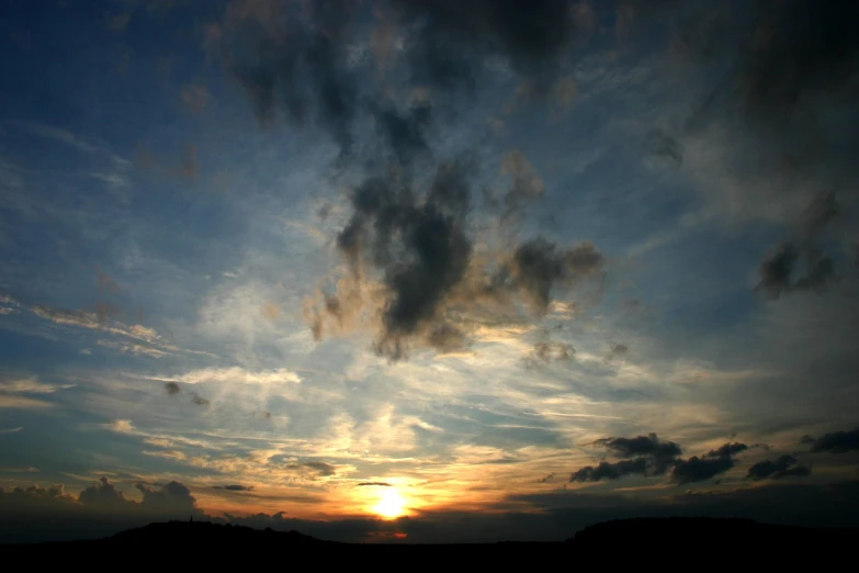 clouds are flying in the sky at sunset