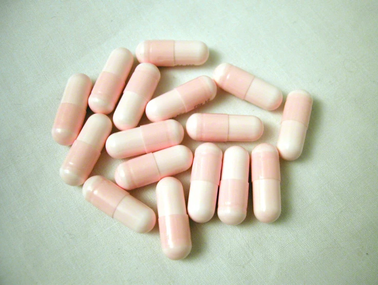 several pink pills on a white surface