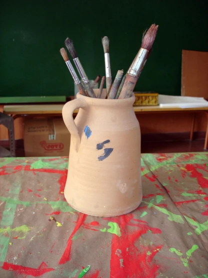 a pottery vase with various brushes in it