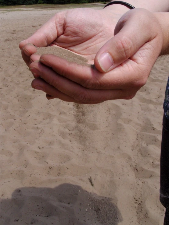 a person holding a sand clock at the beach