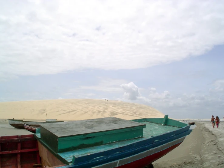 a small boat sitting on top of a sandy beach